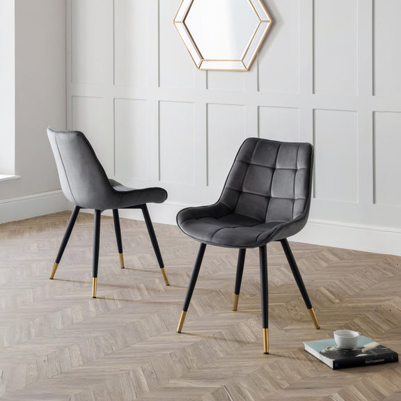 Two modern gray chairs with gold legs on a wooden floor.