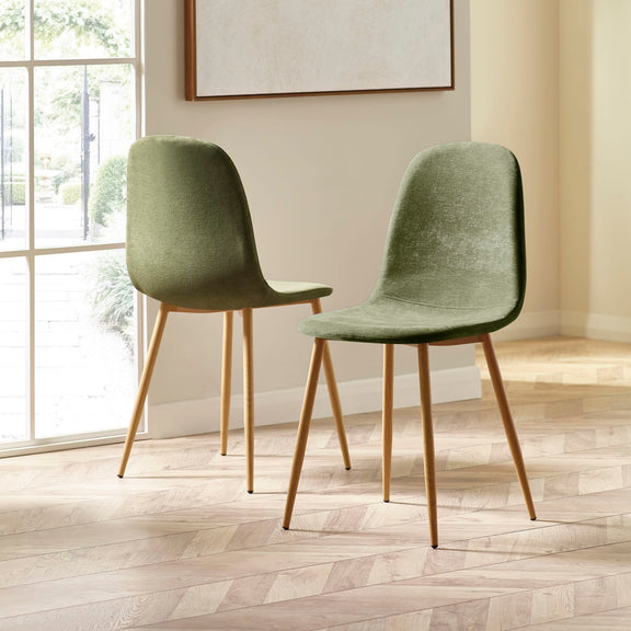 Two green chairs with wooden legs in a room with a large window.