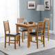 Wooden dining table with chairs in a room with gray walls and a lamp.