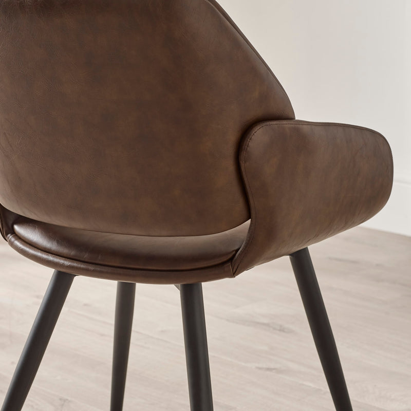 Brown leather chair with black metal legs on a light wooden floor.