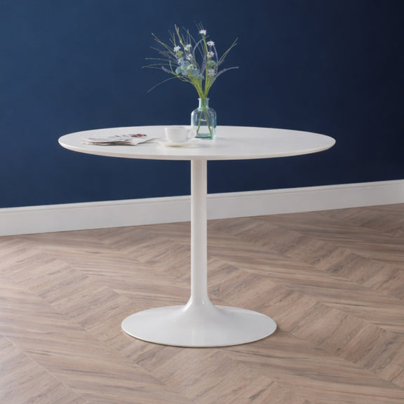 Round white table with a vase of flowers against a blue wall.