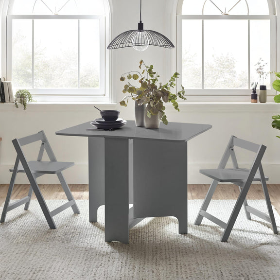 Gray dining table with chairs in a bright room with large windows.