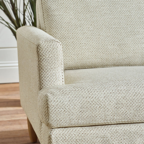 Close-up of a textured beige armchair on a wooden floor.