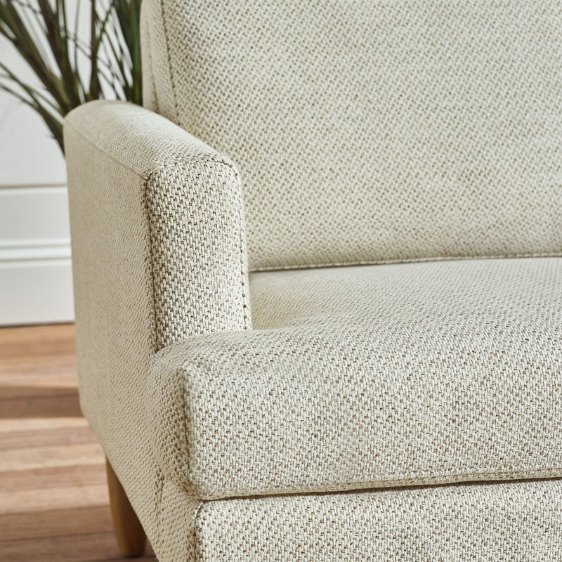 Close-up of a textured beige armchair on a wooden floor.