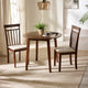 Dining room with a round wooden table and two chairs on a light-colored rug.