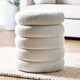Stack of textured round cushions on a rug in a living room setting