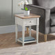 Small side table with a wooden top and white base next to a gray sofa.