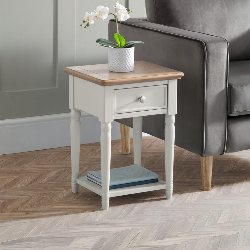 Small side table with a wooden top and white base next to a gray sofa.