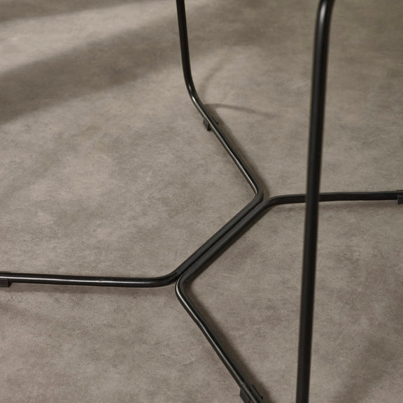 Close-up of a black metal chair frame on a gray concrete floor
