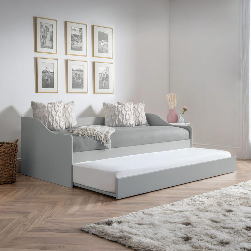 Gray sofa bed with white mattress in a room with framed pictures on the wall.
