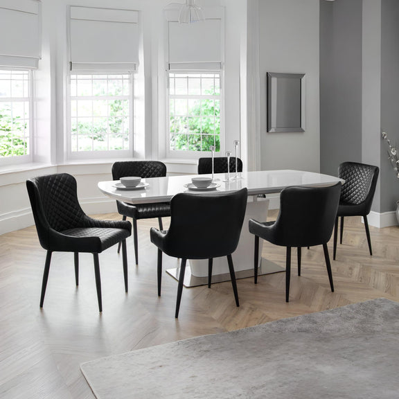 Modern dining room with a round table and black chairs in a bright room.