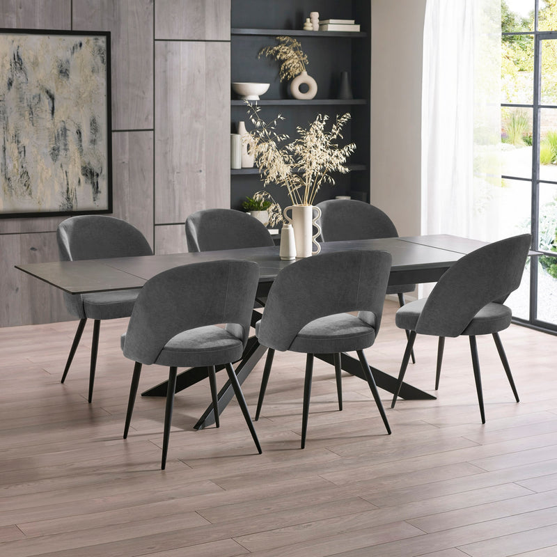 Dining room with a long dark table and six gray chairs in a modern interior setting.