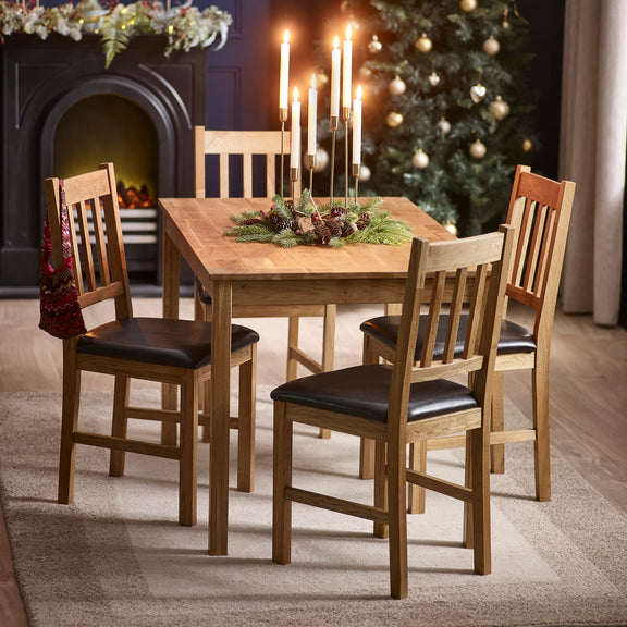 Wooden dining table with chairs in a room decorated for Christmas.