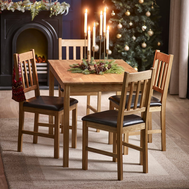 Wooden dining table with chairs in a room decorated for Christmas.