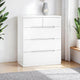 White dresser with four drawers in a room with plants and a rug.
