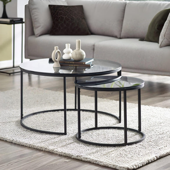 Modern black nesting tables in a living room setting with a sofa and decorative items.