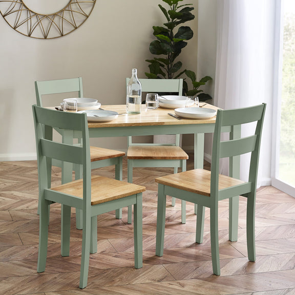 Dining table set with four chairs in a room with a plant and window.