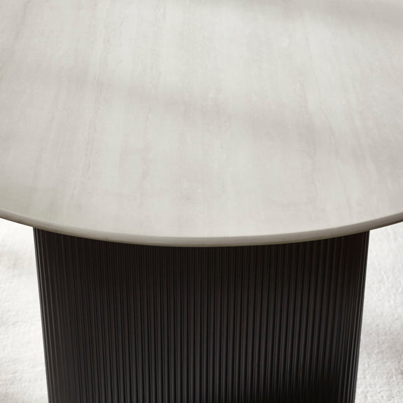 Round table with a light-colored top and dark ribbed base on a neutral background