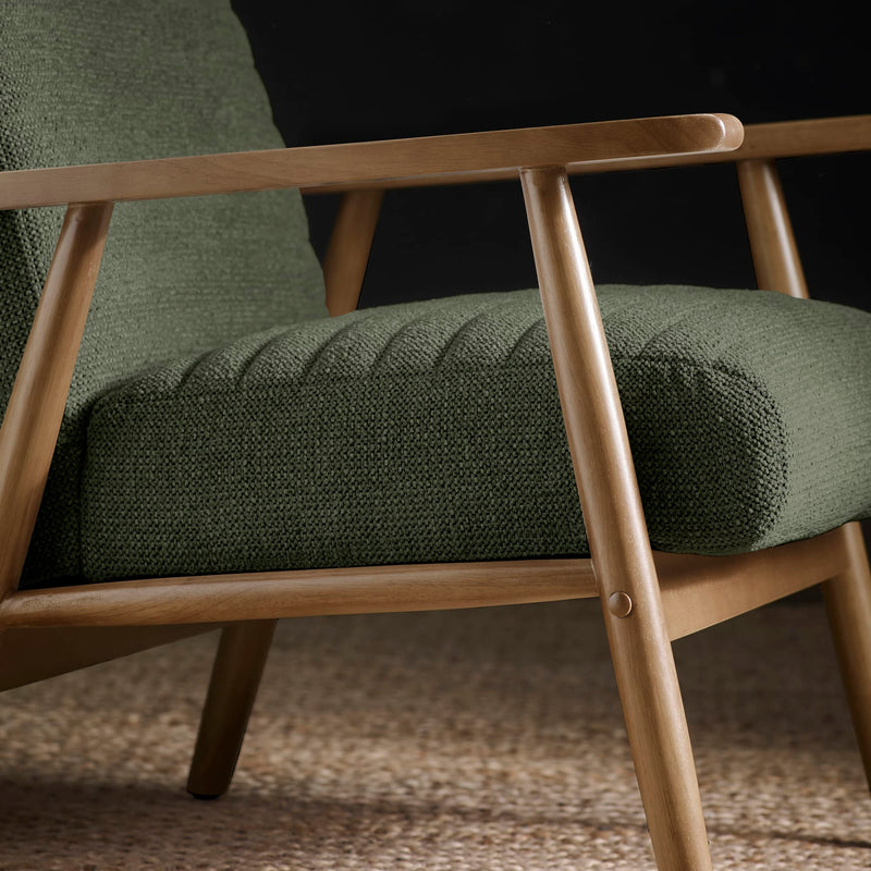 Green upholstered chair with wooden frame on a textured surface