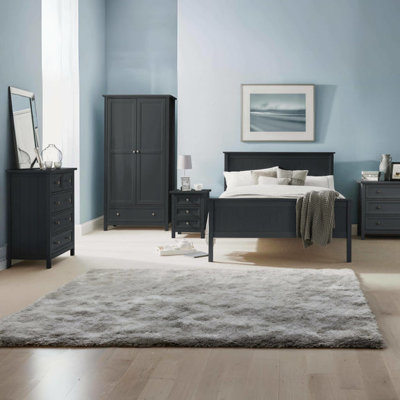 Modern bedroom with black furniture, including a bed, wardrobe, and dressers, against a light blue wall.