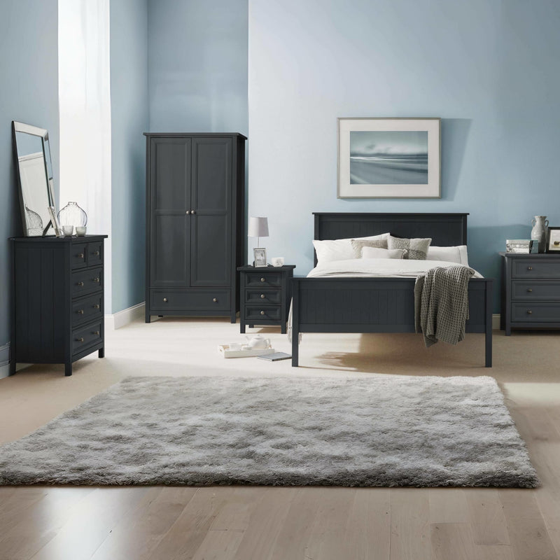 Modern bedroom with black furniture, including a bed, wardrobe, and dressers, against a light blue wall.