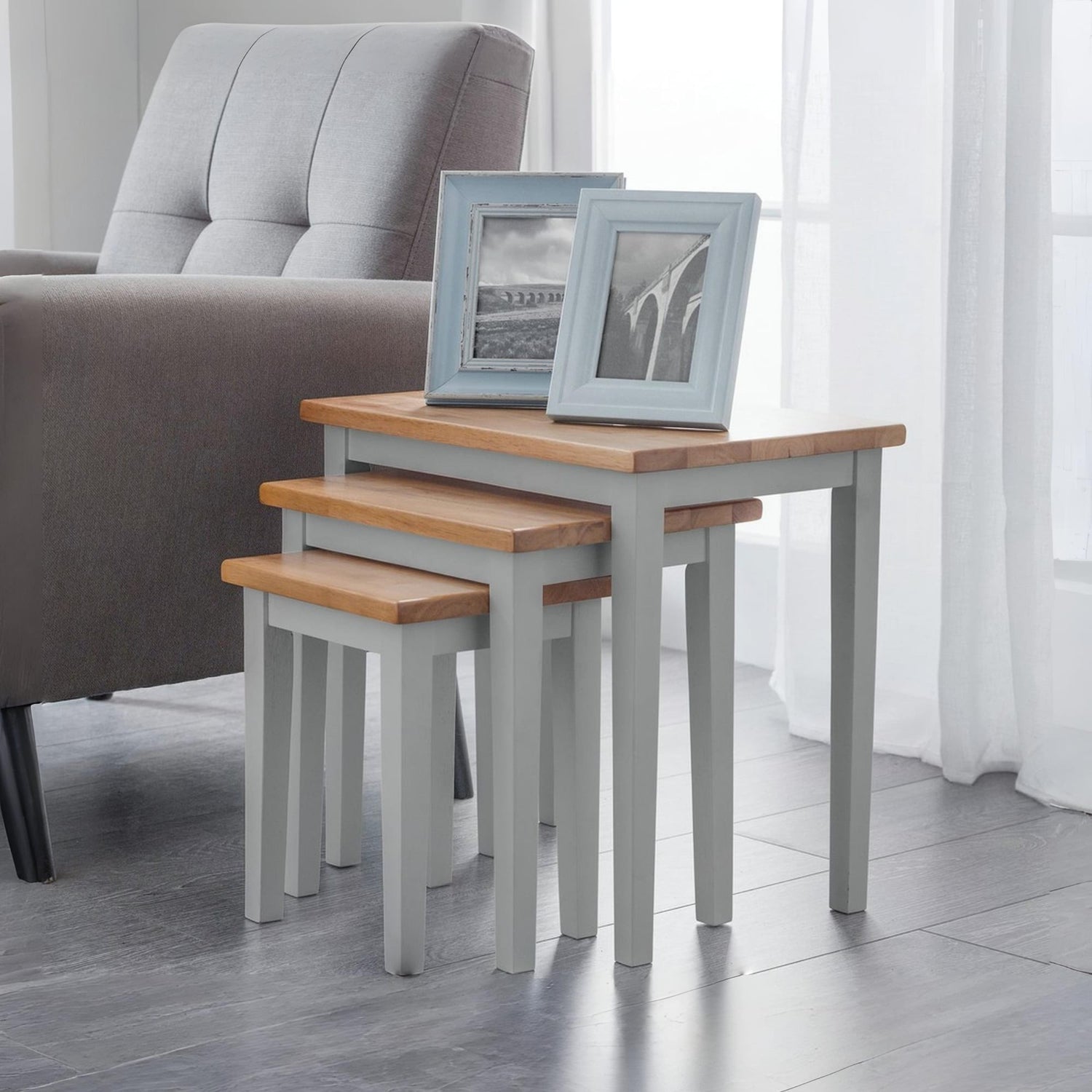 Set of three nesting tables with wooden tops and gray bases in a living room setting.