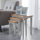 Set of three nesting tables with wooden tops and gray bases in a living room setting.