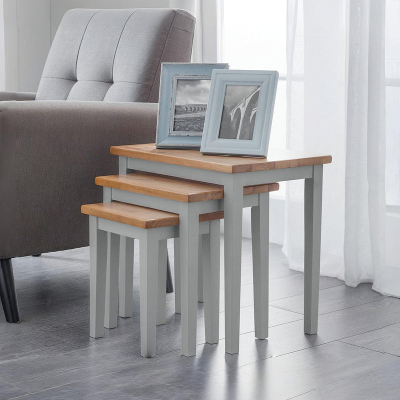 Set of three nesting tables with wooden tops and gray bases in a living room setting.