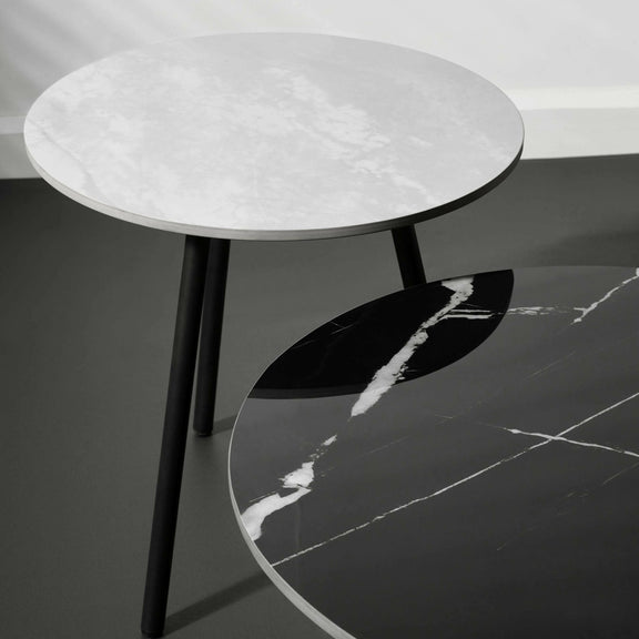 Round marble table with black legs on a dark floor