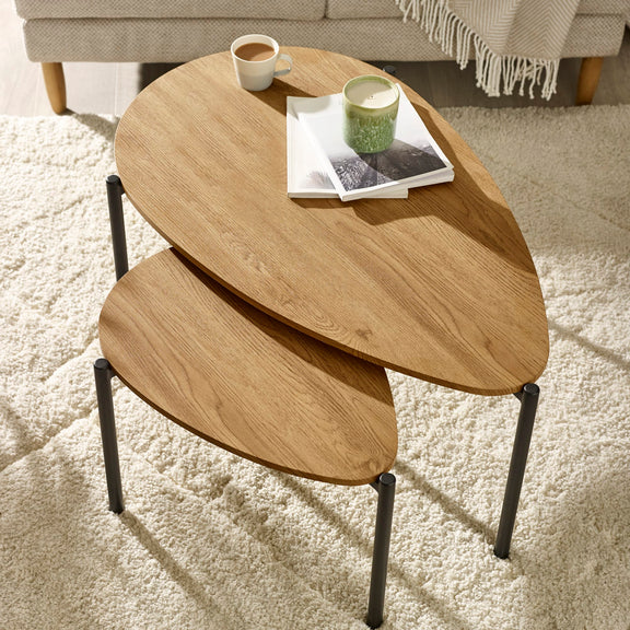Wooden nesting tables with a cup and book on a light-colored rug