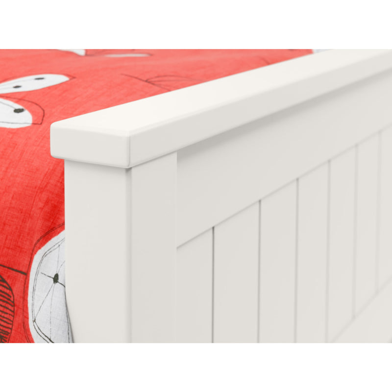White wooden toy box with a red quilted blanket featuring cartoon characters on top.