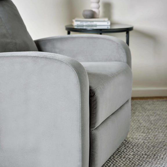 Gray armchair in a room with a small table and decor items.