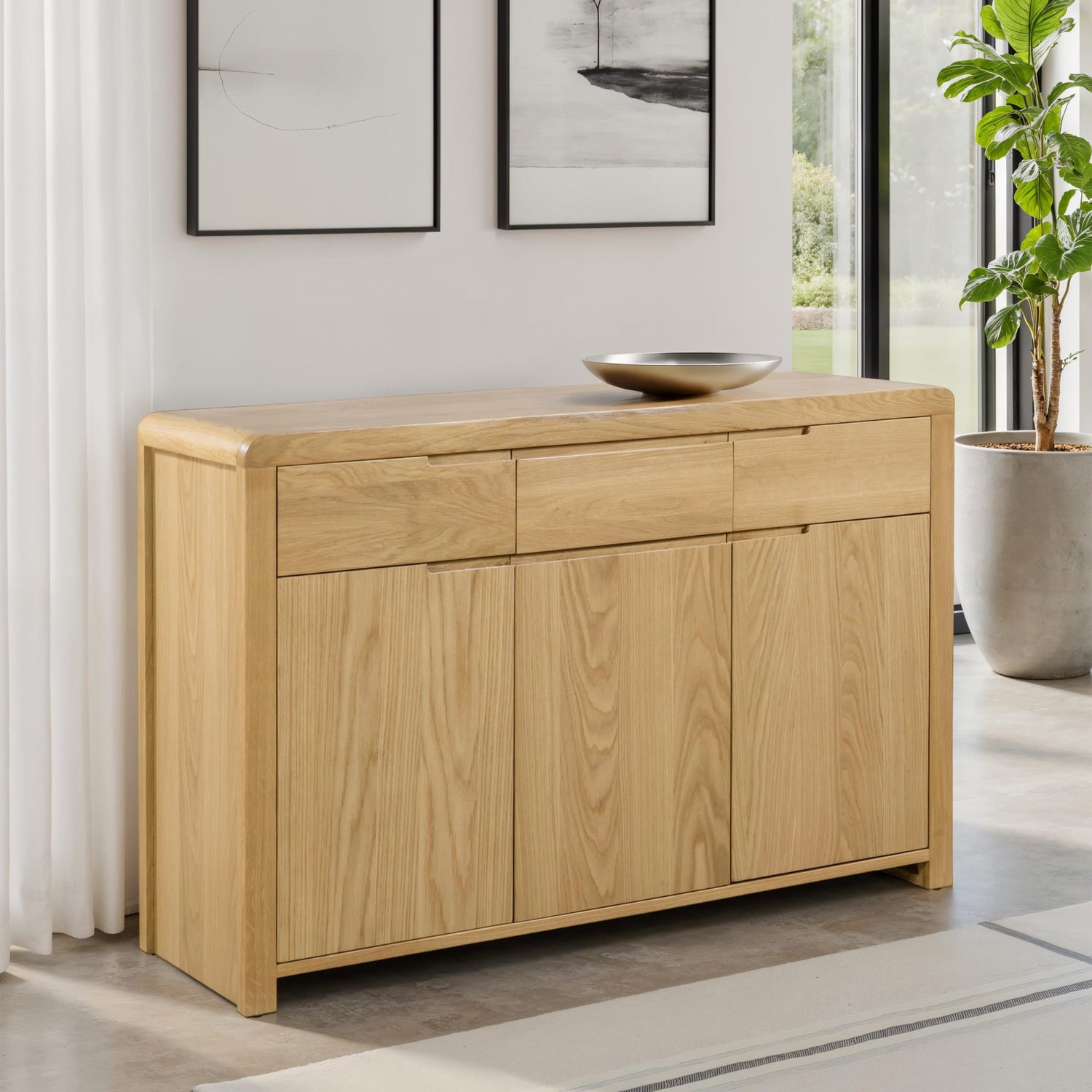 Light wood sideboard in a modern living room with a plant and artwork.