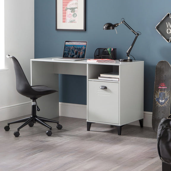 White desk with a laptop, lamp, and office supplies against a blue wall.