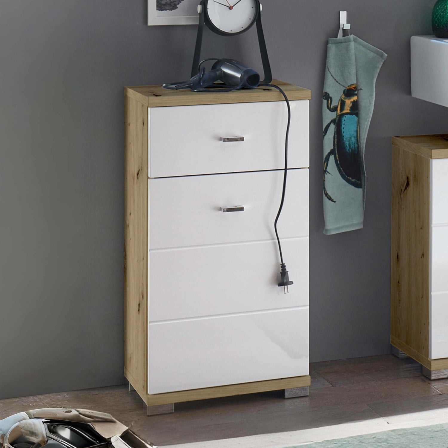 White dresser with wooden accents against a gray wall, with a hair dryer and clock on top.