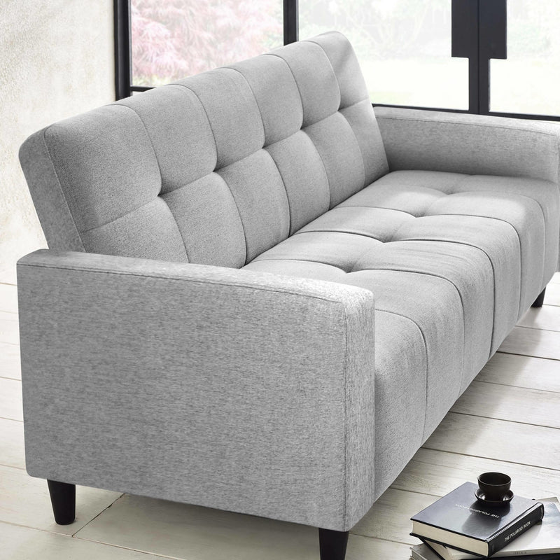 Gray tufted sofa in a room with large windows.