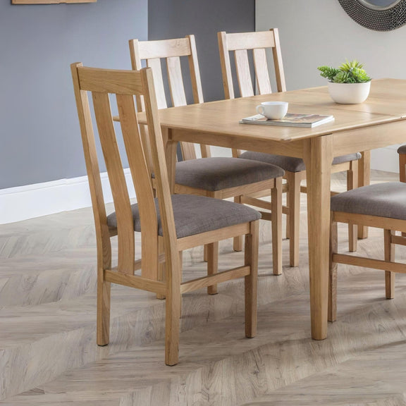 Wooden dining table with chairs in a room with gray walls and wooden flooring.