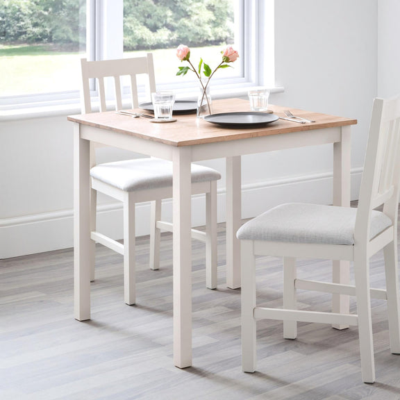 Dining table set with chairs in a room with large windows.