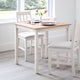 Dining table set with chairs in a room with large windows.
