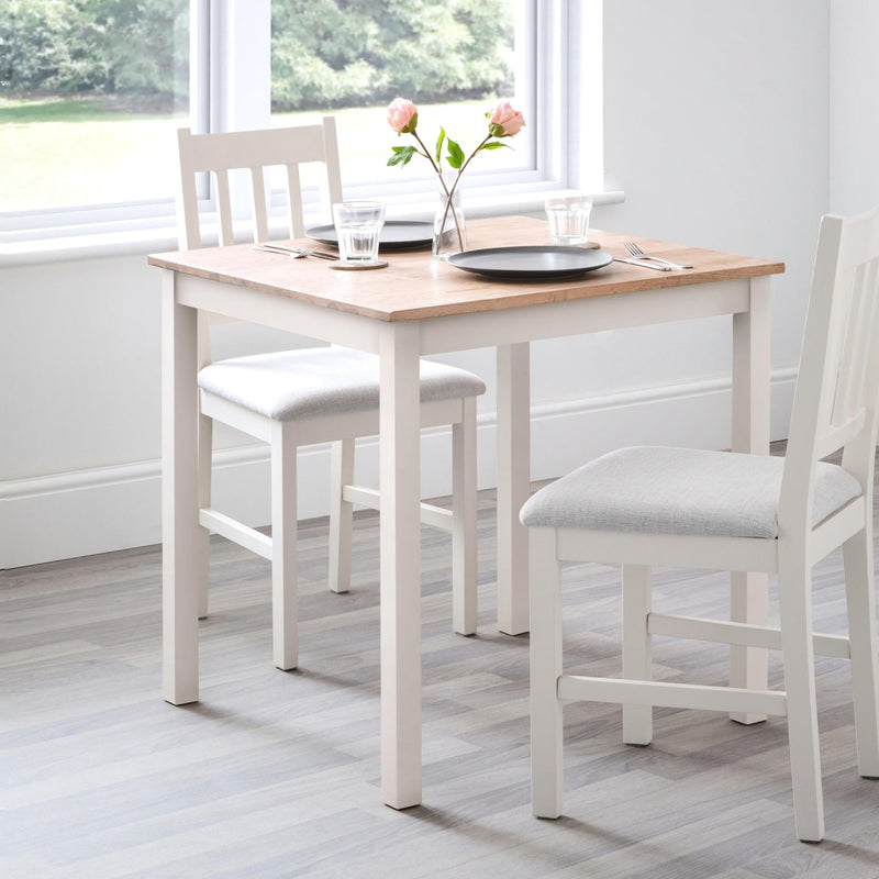 Dining table set with chairs in a room with large windows.