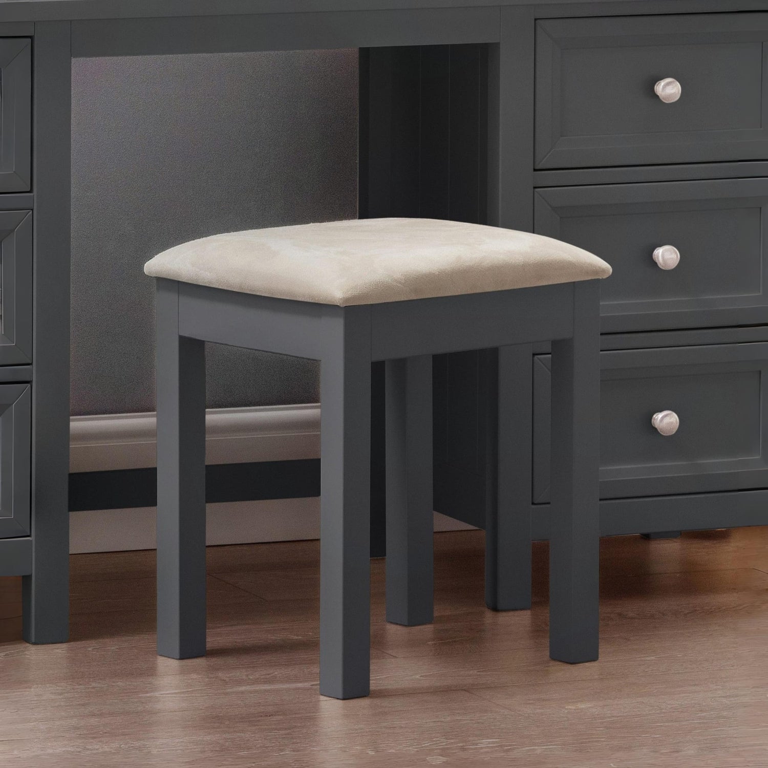 Gray stool with beige cushion in front of a gray dresser.