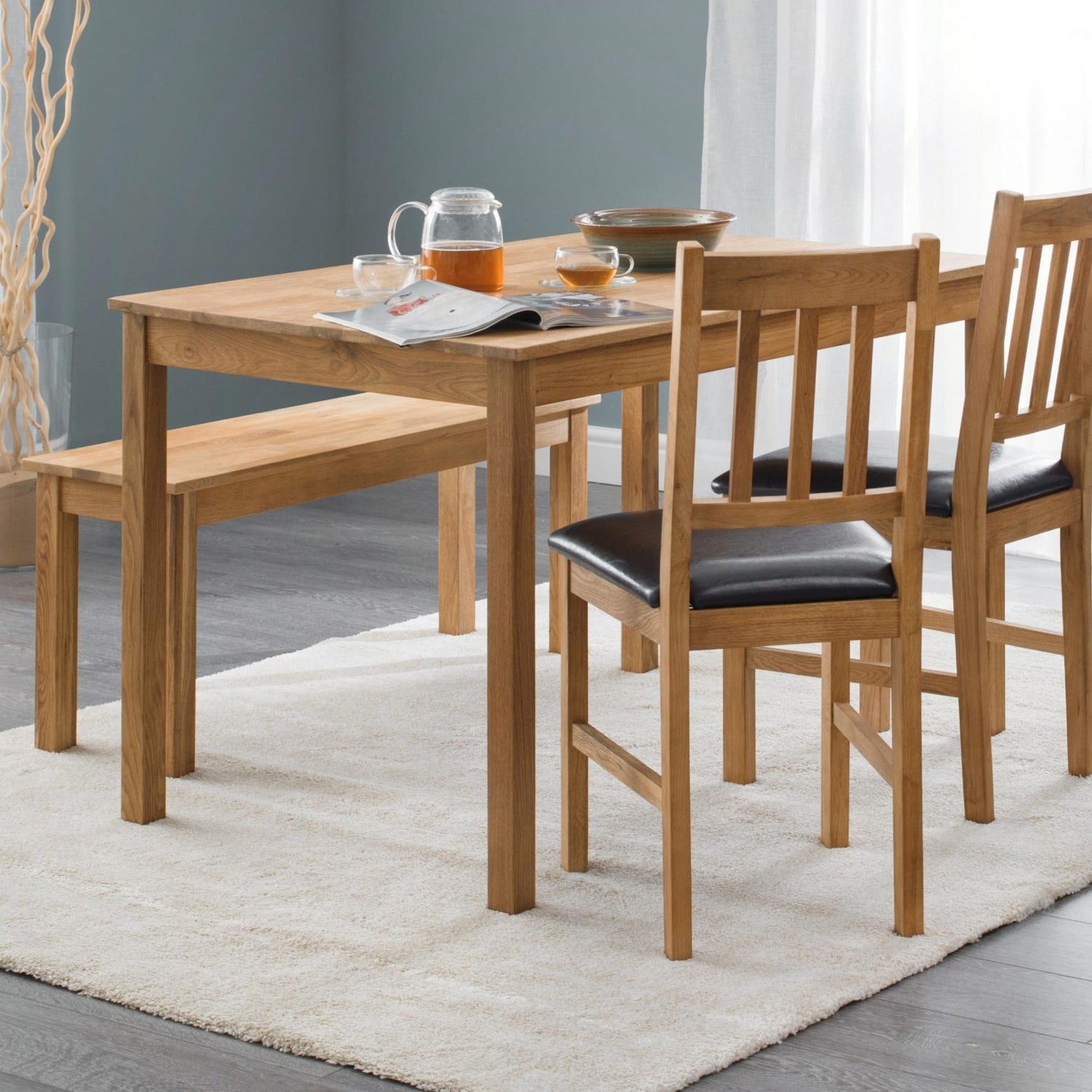 Wooden dining table with chairs and a bench on a light rug.