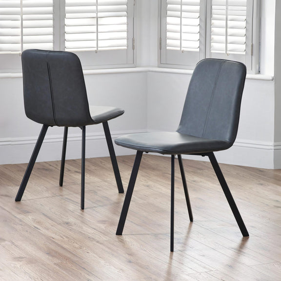 Two black chairs with black legs on a wooden floor.