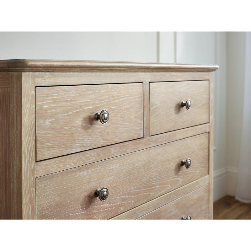 Wooden dresser with four drawers and metal handles on a white wall background