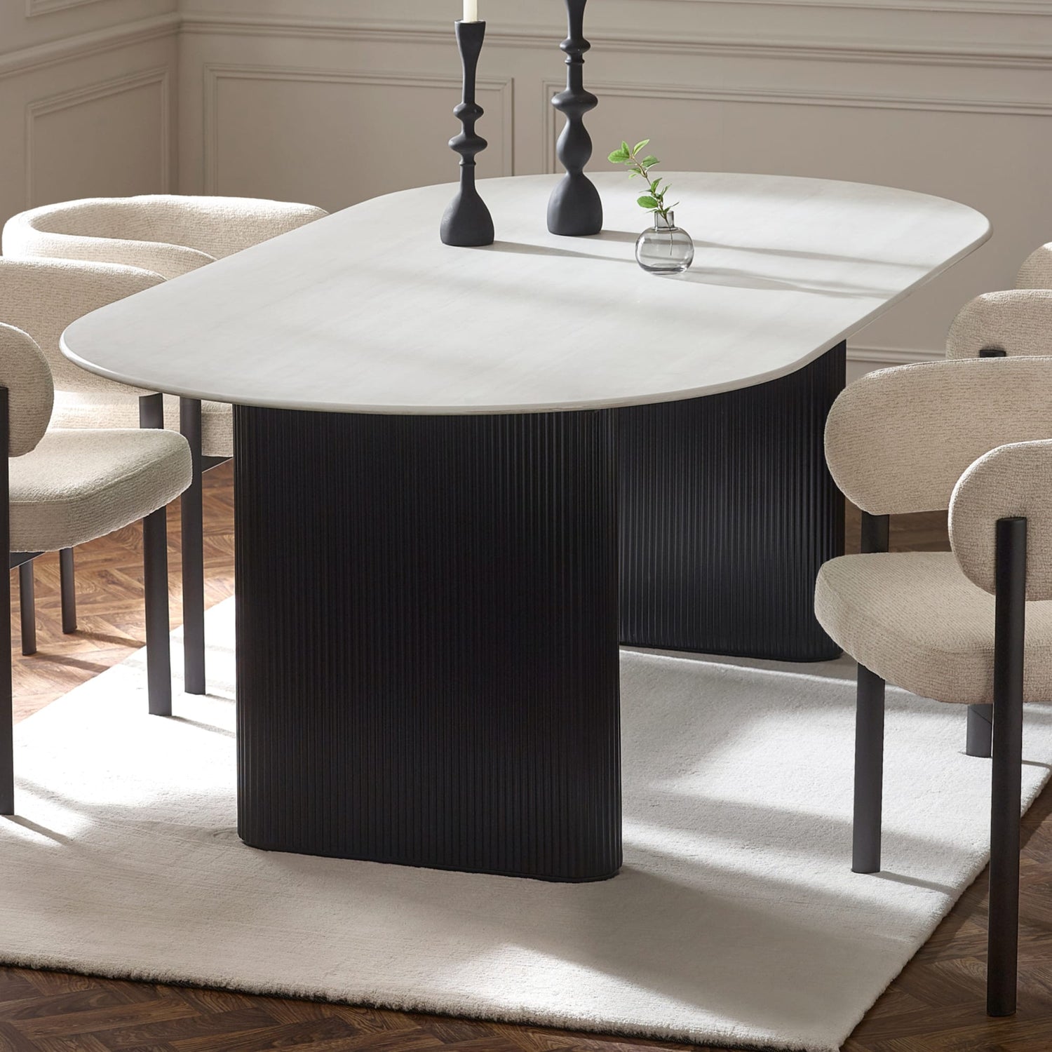 Dining table with black cylindrical base and white marble top in a room setting.