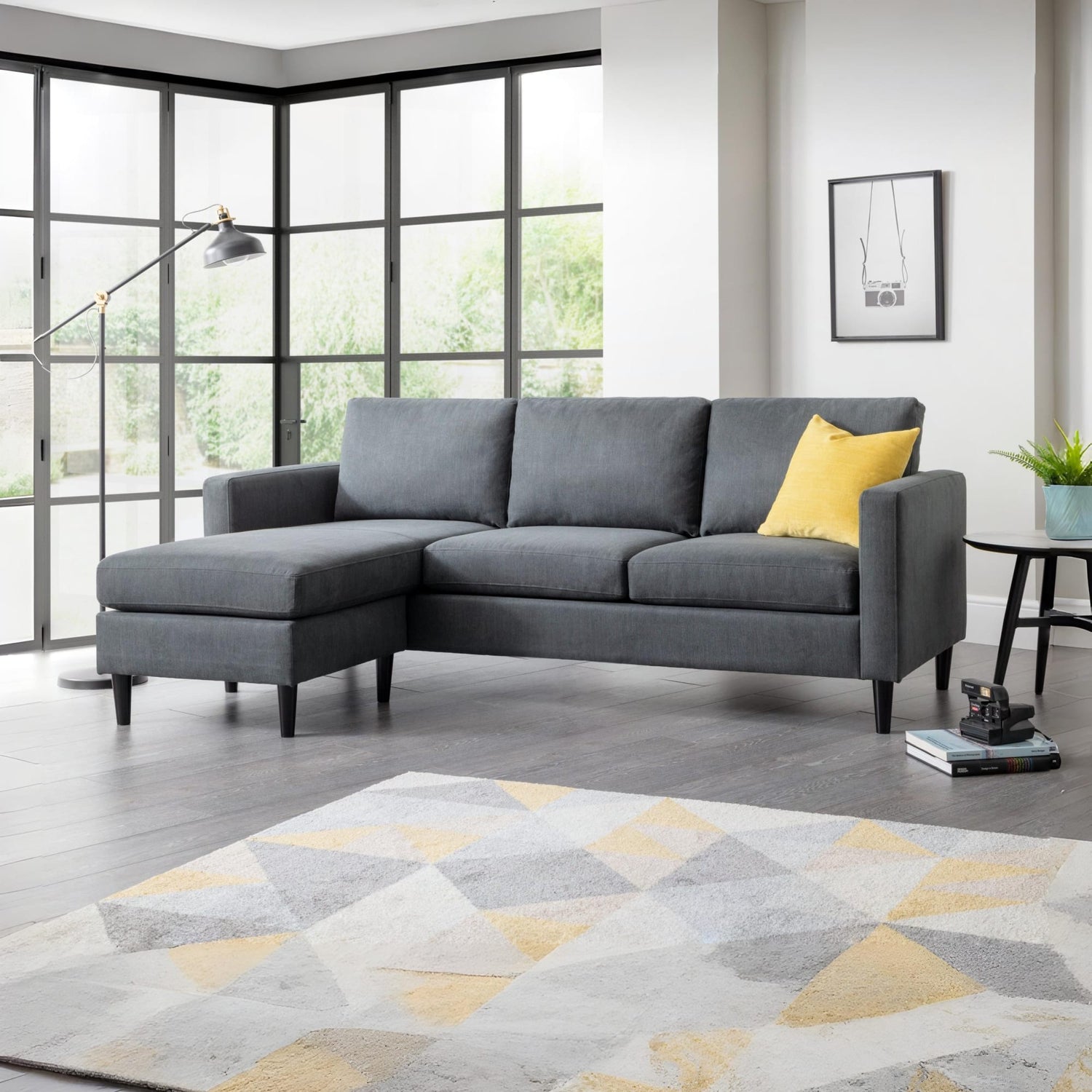 Gray sectional sofa with a yellow pillow in a living room setting.
