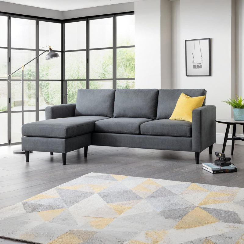 Gray sectional sofa with a yellow pillow in a living room setting.