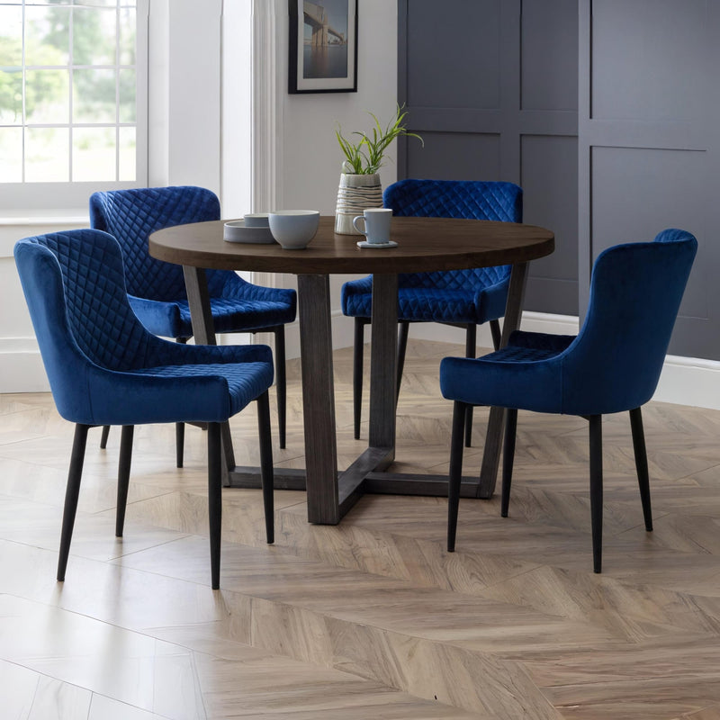 Dining room with a round wooden table and blue chairs.