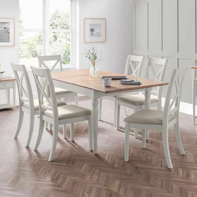Dining room with a wooden table and white chairs on a wooden floor.