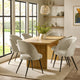 Dining room with wooden table and white chairs near large windows.